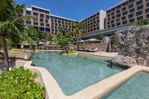 ein Schwimmbad mit einem Resort im Hintergrund in der Unterkunft Sheraton Cebu Mactan Resort in Mactan