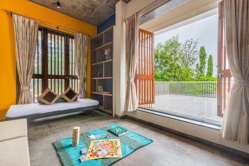 a room with a large window and a table at SaffronStays Amrapali - 5BHK Villa in Nashik with Pool, Lawn & Kids Play Area in Deolāli