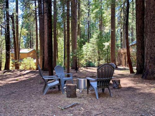 Tres sillas y una mesa en el bosque en The Cedar Loft - Pet and Family Friendly - BBQ/Pool/Fire Pit, en Camp Connell