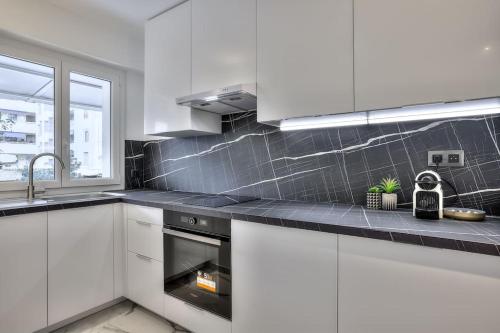 une cuisine avec des armoires blanches et un four à plaques de cuisson dans l'établissement The White Cocoon in Antibes City, à Antibes