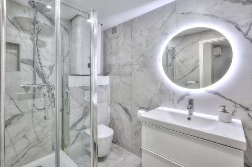 une salle de bain avec une douche, un lavabo et un miroir dans l'établissement The White Cocoon in Antibes City, à Antibes