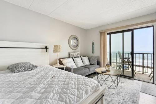 een slaapkamer met een bed, een bank en een balkon bij Beachfront Fourth-Floor Condo with Community Pool! in North Wildwood