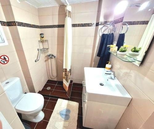 uma casa de banho com um lavatório branco e um WC. em Best View Katechaki Bridge Metro em Atenas