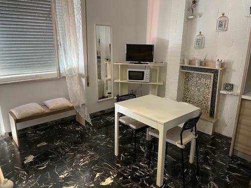 Habitación con mesa blanca, sillas y TV. en Romantik Appartament, en Potenza Picena