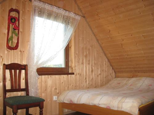 1 dormitorio con cama, ventana y silla en Domek Czerwony Kapturek, en Płocice