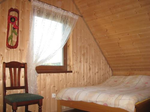 a bedroom with a bed and a window and a chair at Domek Czerwony Kapturek in Płocice