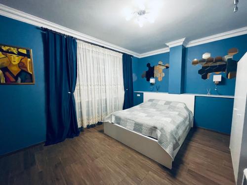 a bedroom with blue walls and a bed in it at Rooms4Rent Cottage in Klaipėda