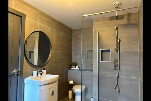 bagno con doccia, lavandino e specchio di Killarney modern family cottage a Killarney