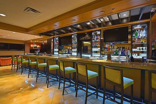 a bar with green chairs in a restaurant at Tulsa Marriott Southern Hills in Tulsa