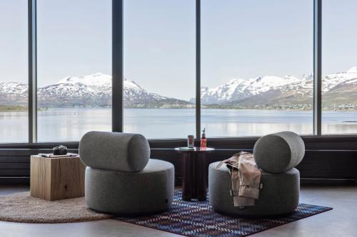 two chairs and a table in a room with snow covered mountains at Moxy Tromso in Tromsø