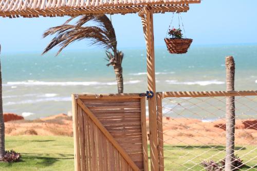 a wooden gate with a palm tree in the background at ASAS DEL MAR - SUITES in Canoa Quebrada