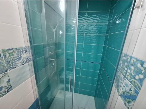a bathroom with a glass shower with blue tiles at DONNA FILOMENA Residence in Marina di Camerota