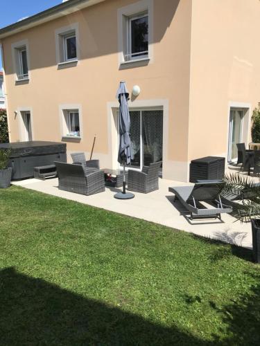 un patio con sillas y una sombrilla frente a una casa en Charmante et agréable chambre dans une villa calme, en Andrézieux-Bouthéon