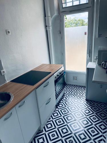 uma cozinha com armários brancos e um piso preto e branco em La pause em Saint-Maur-des-Fossés