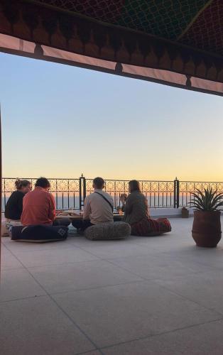 a group of people sitting on the floor watching the sunset at cactus surf house in Tamraght Ouzdar