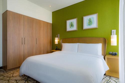 a bedroom with a large white bed and green walls at Element Me'aisam, Dubai in Dubai