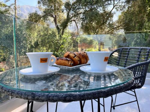 a glass table with two cups and a basket of bread at Maison deluxe studios and apartment in Parga