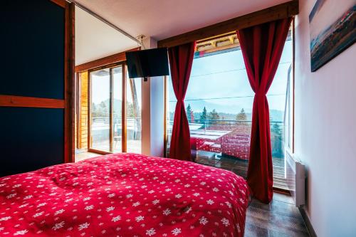 une chambre avec un lit rouge et une grande fenêtre dans l'établissement Mystic Mountain Apartment Chamrousse, à Chamrousse