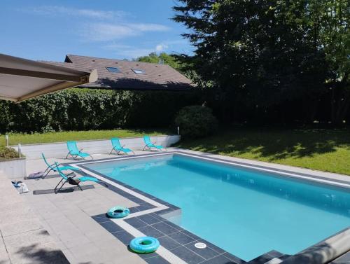 une piscine avec quatre chaises et une piscine dans l'établissement Villa Armonia 5 étoiles avec piscine chauffée jacuzzi et jardin à 3mn du lac d Annecy, à Doussard