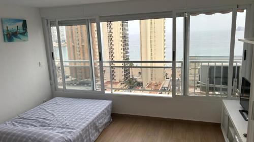 een slaapkamer met een bed en een groot raam bij Ducado 13 Playa Benidorm in Benidorm