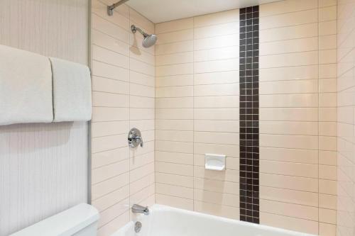 a bathroom with a shower with a tub and a toilet at Delta Hotels by Marriott Burnaby Conference Centre in Burnaby