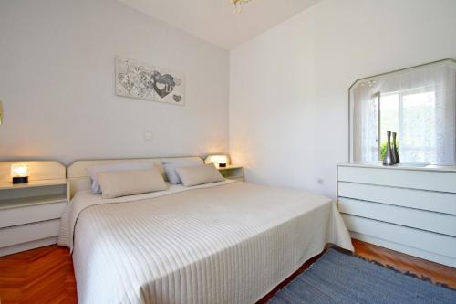 a white bedroom with a bed and a window at Apartment Elvi in Rabac