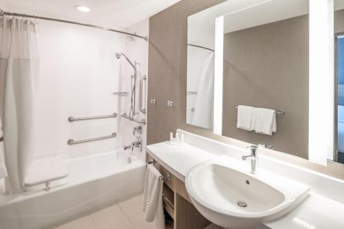 ein Badezimmer mit einem Waschbecken, einer Badewanne und einem Spiegel in der Unterkunft SpringHill Suites Dallas Central Expressway in Dallas