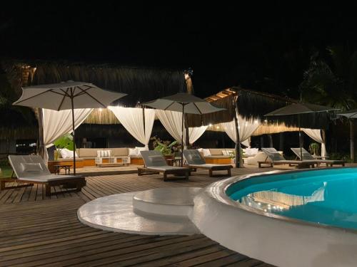 a swimming pool with chairs and umbrellas on a deck at Entre Palmeras in Bocapán