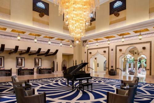 a grand piano in a lobby with a chandelier at Sharq Village & Spa, a Ritz-Carlton Hotel in Doha