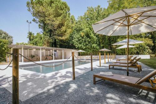 una piscina con bancos y sombrillas junto a un complejo en Best Western Hotel Cristallo Mantova, en Virgilio