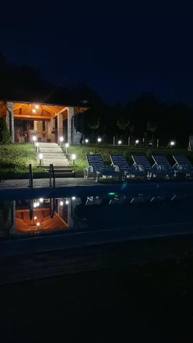 a group of chairs sitting next to a pool at night at House_Zoi in Čelinac