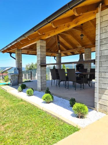 a patio with a table and chairs under a wooden roof at House_Zoi in Čelinac
