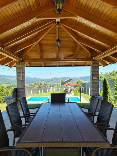 a wooden table and chairs under a wooden pergola at House_Zoi in Čelinac