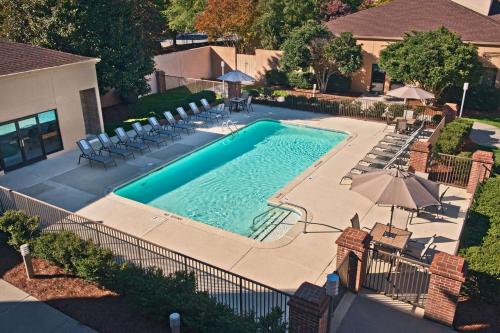 uma vista superior para uma piscina com cadeiras e guarda-sóis em Sonesta Select Raleigh Durham Airport Morrisville em Morrisville