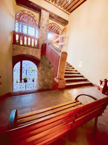 an empty pew in a room with a staircase at HOTEL PLAZA VASCO in Pátzcuaro