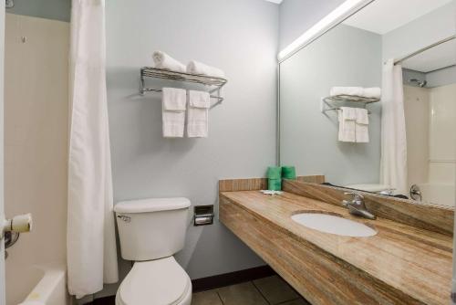 a bathroom with a toilet and a sink and a mirror at Rodeway Inn Conference Center in Beaumont