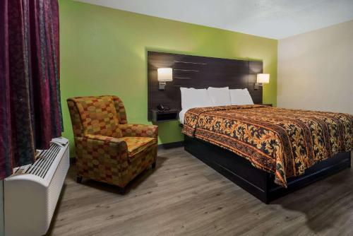 Habitación de hotel con cama y silla en Rodeway Inn Conference Center, en Beaumont