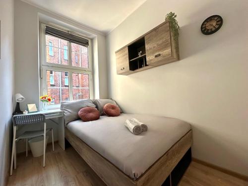 a bed in a room with a desk and a window at MMRent Gold Room in Gdańsk