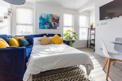 a blue couch with yellow pillows in a living room at 2 bed apartment near the beach in Southend-on-Sea