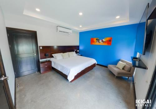 sypialnia z białym łóżkiem i niebieską ścianą w obiekcie Jm House w mieście Alajuela