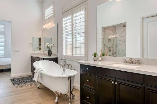 uma casa de banho com uma banheira, um lavatório e um espelho. em Stylish Luxury Signature PGA with Private Pool & Golf Cart. LIC# 259358 - 4 Bedrooms em La Quinta