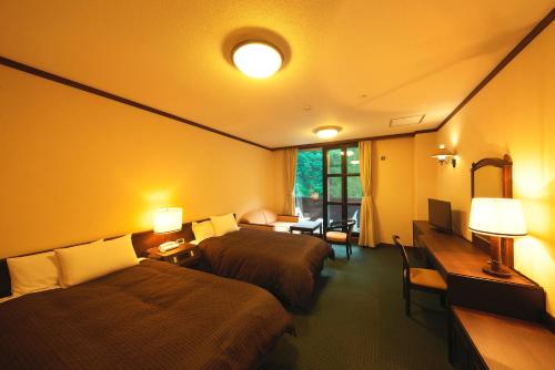 a hotel room with two beds and a desk at Hotel Hotaka in Takayama