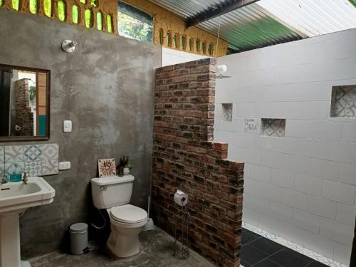 baño con aseo y pared de ladrillo en ¡Habitación en un Bus!, en La Calera