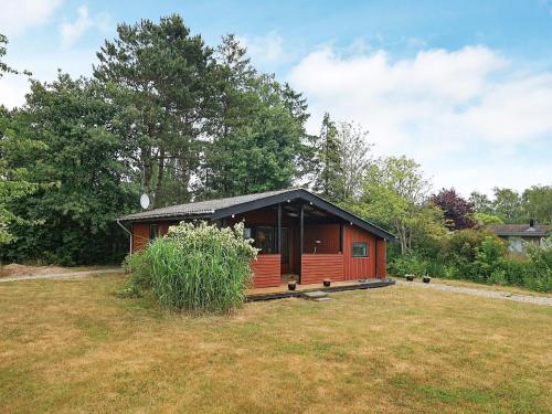 a small red cabin in a yard with a field at 6 person holiday home in Stubbekøbing-By Traum in Stubbekøbing