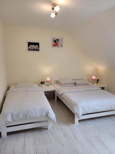 two beds in a white room with two lamps at Villa Grunwald - dom z działką 3000m2 na wyłączność, z dużym ogrodem, tarasem, grillem, hamakami, domkiem dla dzieci i boiskiem in Gierzwałd