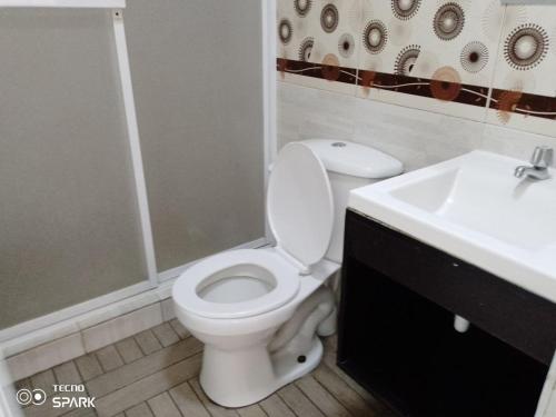 a bathroom with a white toilet and a sink at HOSPEDAJE YACUCALLE in Ibarra