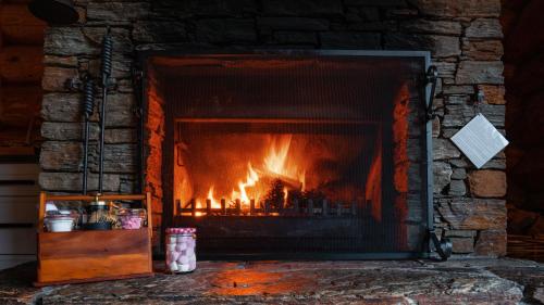 a stone fireplace with a fire in it at Cascade Creek Retreat - near Dunedin in Milton