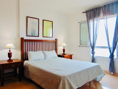 een slaapkamer met een bed en een raam met blauwe gordijnen bij Vista al Mar Fuerteventura in Puerto del Rosario