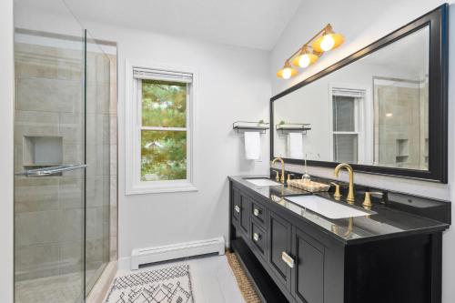 y baño con lavabo, espejo y ducha. en Gorogeous Chic 2BDR Renovated Home near Downtown Sleeps 6 843, en Traverse City
