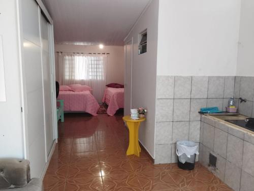 a room with a kitchen and a bedroom with pink beds at Pousada Guaíra in Guaíra